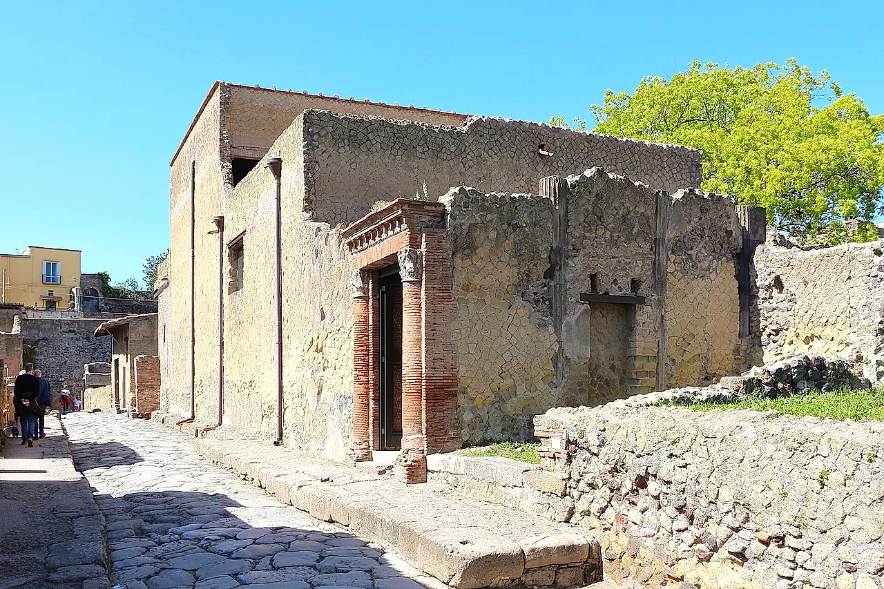Una calle pavimentada y la entrada con columnas de ladrillo de la Casa del Gran Portal