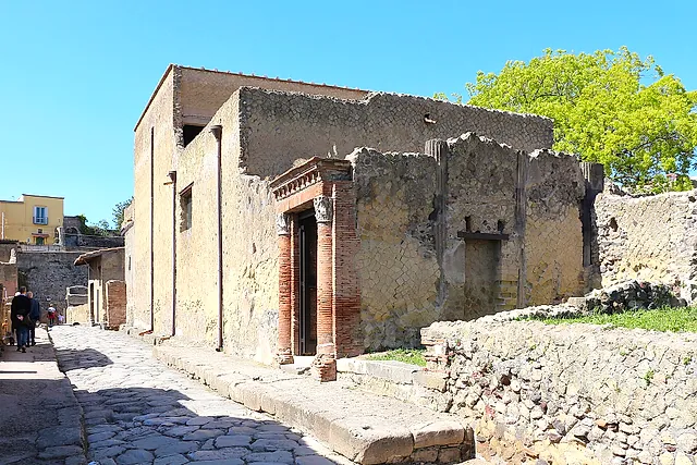 Una calle pavimentada y la entrada con columnas de ladrillo de la Casa del Gran Portal